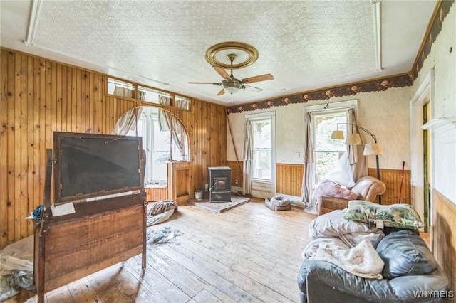 6192 Scudder Rd, Bath, NY 14879 - bedroom featuring wooden walls, wood-type flooring, a wood stove, wainscoting, and ceiling fan