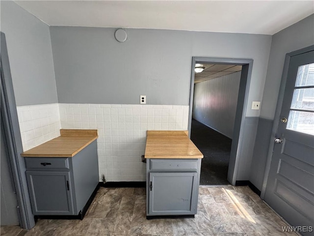 360 Longnecker St, Buffalo, NY 14206 - kitchen with gray cabinetry, wainscoting, tile walls, butcher block counters, and stone finish floors