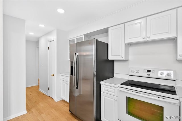kitchen with electric stove, stainless steel refrigerator with ice dispenser, light wood-style floors, white cabinets, and light countertops