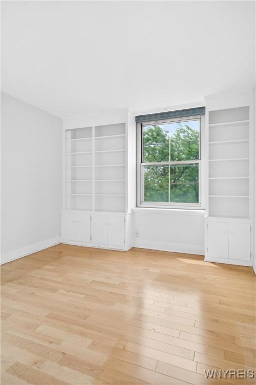 spare room featuring light wood-style flooring and built in features