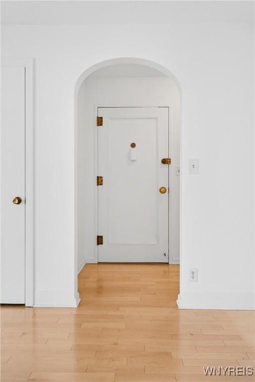 corridor with arched walkways and wood finished floors