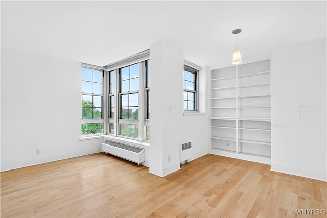 empty room with radiator, light wood finished floors, and plenty of natural light