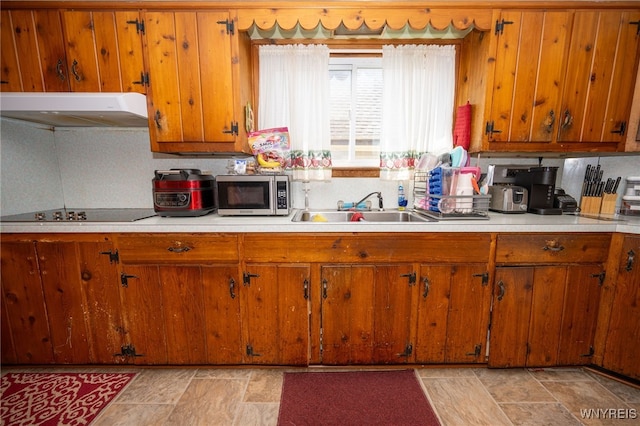 2363 Niagara St, Buffalo, NY 14207 - kitchen with stainless steel microwave, exhaust hood, black electric cooktop, stone finish flooring, and brown cabinets