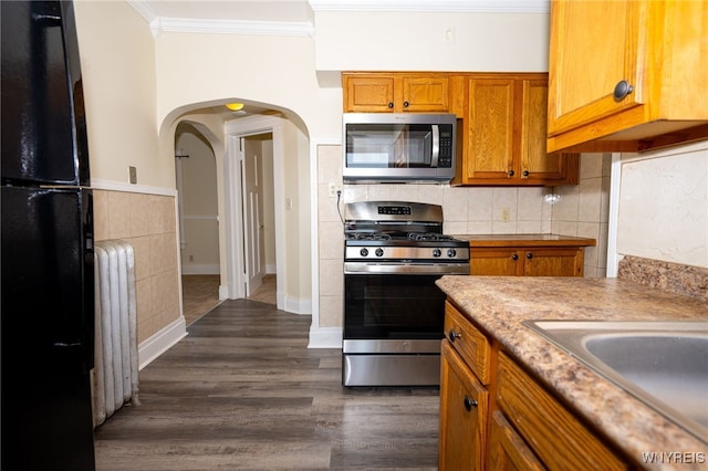 2363 Niagara St, Buffalo, NY 14207 - kitchen featuring stainless steel appliances, ornamental molding, radiator heating unit, brown cabinetry, and arched walkways