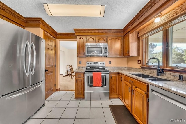 6103 Reger Dr, Lockport Town, NY 14094 - kitchen featuring stainless steel appliances, a textured ceiling, brown cabinetry, light stone countertops, and light tile patterned floors