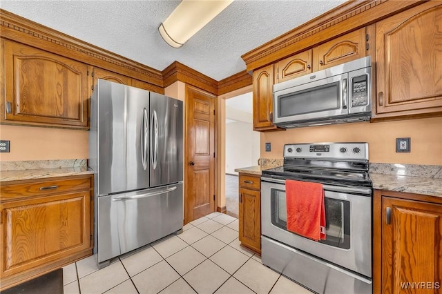6103 Reger Dr, Lockport Town, NY 14094 - kitchen with stainless steel appliances, brown cabinetry, light tile patterned floors, and a textured ceiling