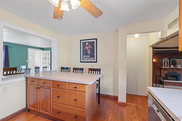 419 Bronson Rd, Geddes, NY 13219 - kitchen featuring light countertops, a kitchen bar, a ceiling fan, light wood-style flooring, and stainless steel dishwasher