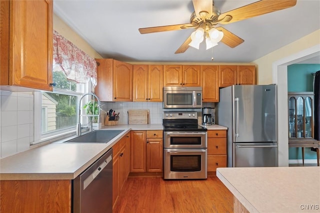 419 Bronson Rd, Geddes, NY 13219 - kitchen with stainless steel appliances, light countertops, light wood-style floors, a ceiling fan, and decorative backsplash