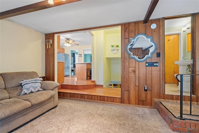 419 Bronson Rd, Geddes, NY 13219 - living area featuring beam ceiling, carpet flooring, wood walls, and a ceiling fan