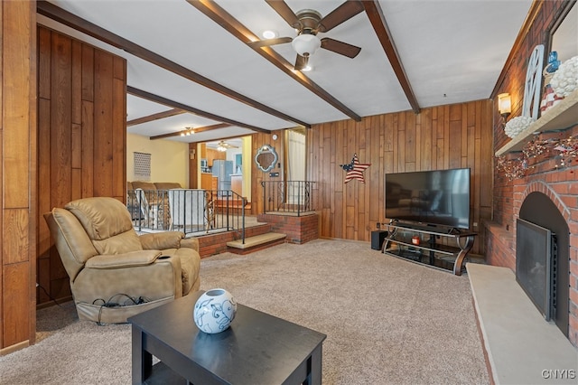 419 Bronson Rd, Geddes, NY 13219 - living area featuring ceiling fan, beam ceiling, a brick fireplace, carpet, and wooden walls