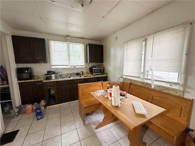 380 Sawyer St, Rochester, NY 14619 - kitchen with stainless steel microwave, a drop ceiling, light countertops, light tile patterned floors, and dark brown cabinetry