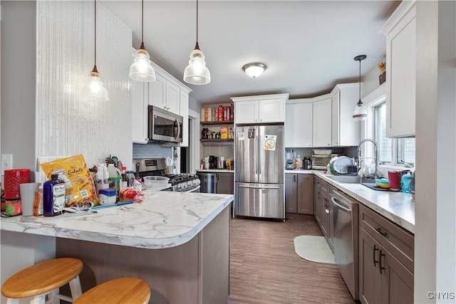 423 Highland Ave, Dewitt, NY 13057 - kitchen featuring stainless steel appliances, tasteful backsplash, a peninsula, white cabinetry, and pendant lighting
