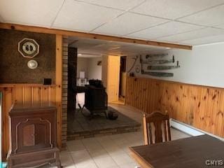 884 Kibby Rd, Lysander, NY 13027 - bar featuring a wood stove, wooden walls, wainscoting, tile patterned flooring, and a paneled ceiling