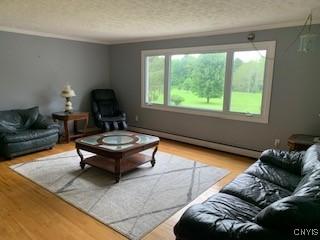884 Kibby Rd, Lysander, NY 13027 - living area with wood finished floors, baseboard heating, a textured ceiling, and crown molding