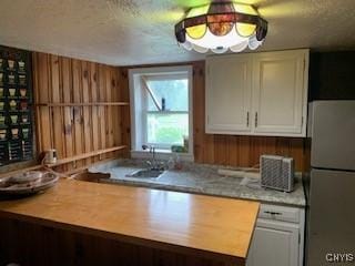 884 Kibby Rd, Lysander, NY 13027 - kitchen featuring freestanding refrigerator, white cabinetry, and wooden walls