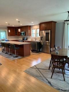 884 Kibby Rd, Lysander, NY 13027 - kitchen featuring appliances with stainless steel finishes, light wood-style flooring, a breakfast bar area, recessed lighting, and glass insert cabinets