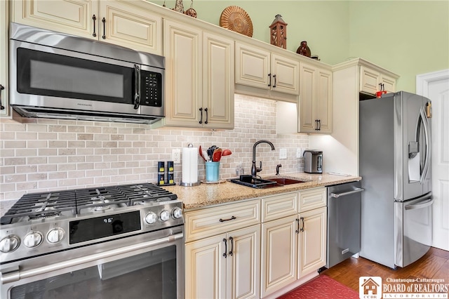 743 Legacy Dr Unit 209, Lewiston, NY 14092 - kitchen with stainless steel appliances, cream cabinets, tasteful backsplash, and light stone countertops