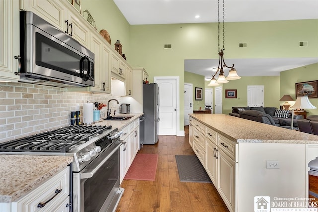 743 Legacy Dr Unit 209, Lewiston, NY 14092 - kitchen featuring stainless steel appliances, wood finished floors, a towering ceiling, open floor plan, and a center island