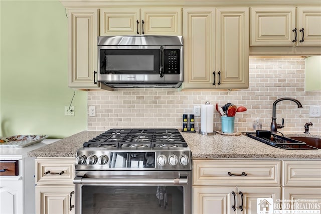 743 Legacy Dr Unit 209, Lewiston, NY 14092 - kitchen with cream cabinets, stainless steel appliances, decorative backsplash, and light stone counters