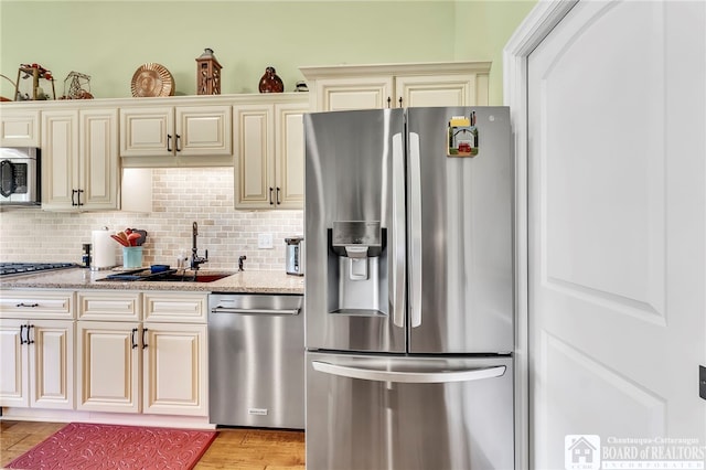 743 Legacy Dr Unit 209, Lewiston, NY 14092 - kitchen featuring appliances with stainless steel finishes, cream cabinets, light stone countertops, and decorative backsplash