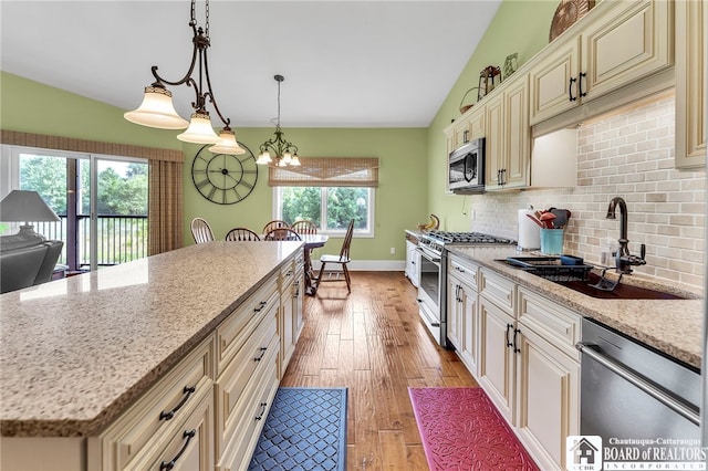 743 Legacy Dr Unit 209, Lewiston, NY 14092 - kitchen with appliances with stainless steel finishes, cream cabinets, lofted ceiling, tasteful backsplash, and light wood-style floors