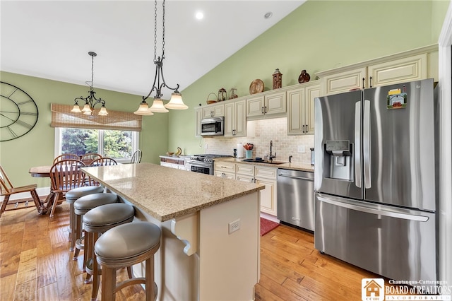 743 Legacy Dr Unit 209, Lewiston, NY 14092 - kitchen with stainless steel appliances, a center island, lofted ceiling, light wood-type flooring, and a breakfast bar