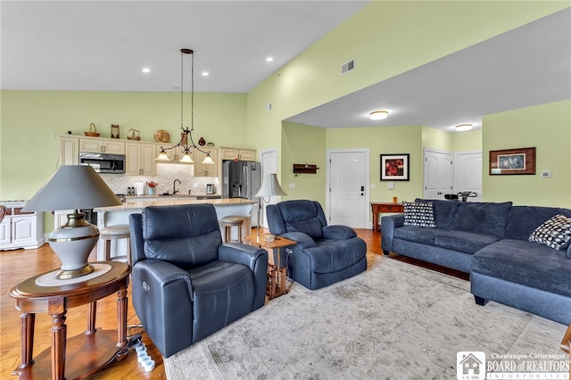 743 Legacy Dr Unit 209, Lewiston, NY 14092 - living room featuring light wood-style floors, a towering ceiling, and recessed lighting