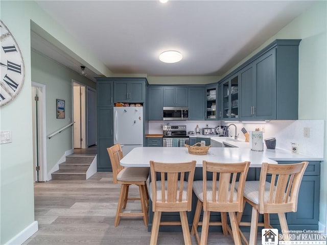 5301 E Lake Rd Unit 23, Chautauqua, NY 14728 - kitchen featuring stainless steel appliances, a peninsula, glass insert cabinets, a kitchen bar, and light countertops