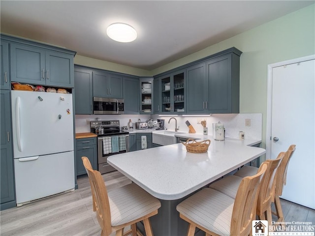 5301 E Lake Rd Unit 23, Chautauqua, NY 14728 - kitchen featuring stainless steel appliances, a peninsula, glass insert cabinets, a kitchen breakfast bar, and light countertops