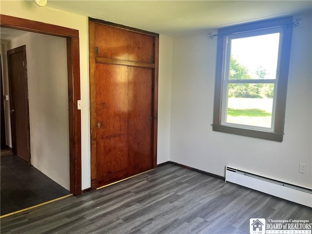 70 Williams Ave, Wellsville, NY 14895 - unfurnished bedroom with baseboard heating, dark wood-style flooring, and a closet