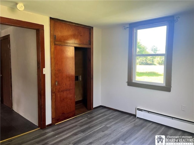 70 Williams Ave, Wellsville, NY 14895 - unfurnished bedroom with baseboard heating, dark wood finished floors, and a closet