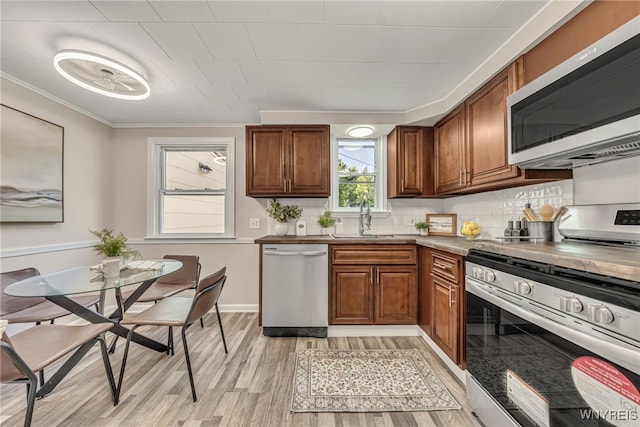112 Southgate Rd, Cheektowaga, NY 14215 - kitchen featuring appliances with stainless steel finishes, crown molding, light wood-type flooring, brown cabinets, and backsplash