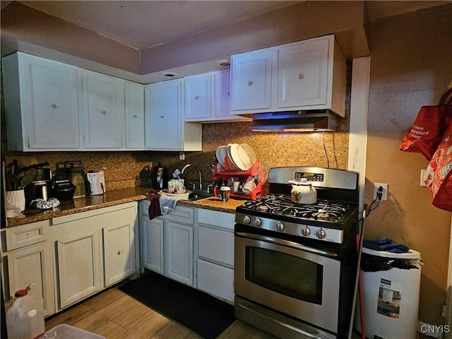 1125 Adams St, Utica, NY 13501 - kitchen with stainless steel gas stove, under cabinet range hood, white cabinets, and light wood finished floors