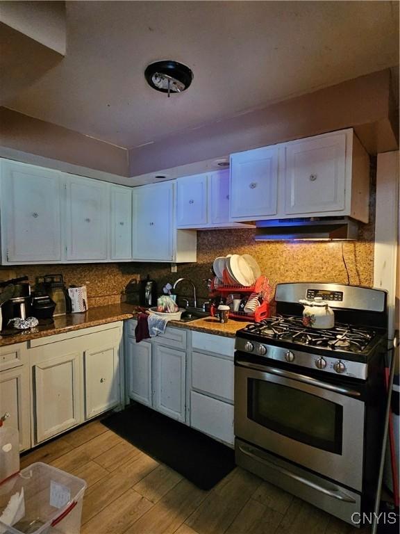 1125 Adams St, Utica, NY 13501 - kitchen featuring stainless steel gas range, extractor fan, wood finished floors, and white cabinets