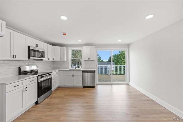 105 Benoit Dr, Geddes, NY 13209 - kitchen featuring appliances with stainless steel finishes, backsplash, light countertops, white cabinetry, and light wood-style floors