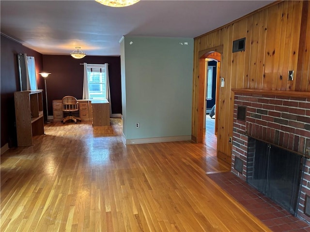 20-22 N Belmont Cir, Oneonta, NY 13820 - unfurnished living room with wood finished floors, arched walkways, a fireplace, ornamental molding, and wood walls
