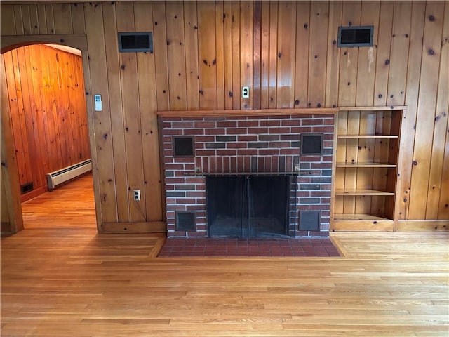 20-22 N Belmont Cir, Oneonta, NY 13820 - detailed view of a baseboard heating unit, wood finished floors, a fireplace, wooden walls, and arched walkways
