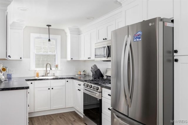 451 Moore Ave, Tonawanda, NY 14223 - kitchen with appliances with stainless steel finishes, dark countertops, white cabinetry, decorative backsplash, and wood finished floors