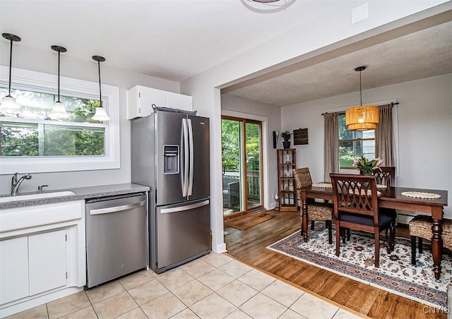 112 Haverhill Dr, Dewitt, NY 13214 - kitchen featuring appliances with stainless steel finishes, light tile patterned floors, white cabinetry, and hanging light fixtures