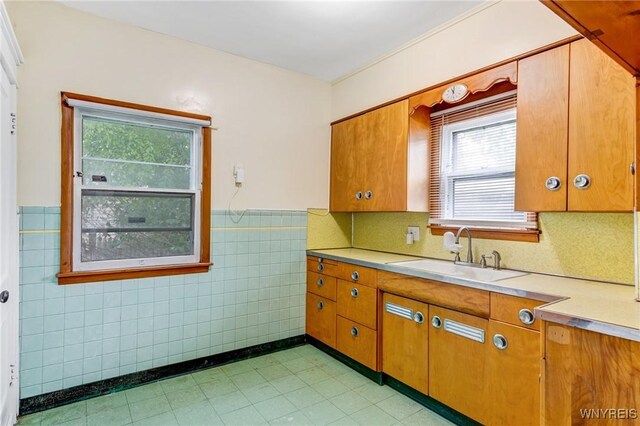 2239 Willow Ave, Niagara Falls, NY 14305 - kitchen featuring light countertops, wainscoting, tile walls, and brown cabinets
