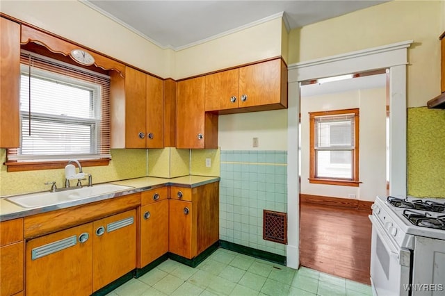 2239 Willow Ave, Niagara Falls, NY 14305 - kitchen featuring white range with gas stovetop, brown cabinets, light tile patterned flooring, crown molding, and light countertops