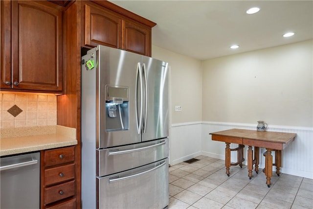 11 Walnut St, Phelps, NY 14533 - kitchen featuring appliances with stainless steel finishes, wainscoting, light countertops, light tile patterned floors, and brown cabinetry