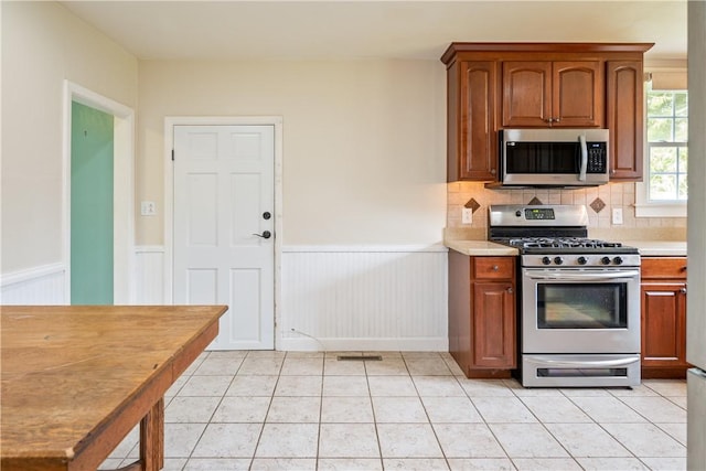11 Walnut St, Phelps, NY 14533 - kitchen featuring stainless steel appliances, wainscoting, light tile patterned flooring, light countertops, and tasteful backsplash