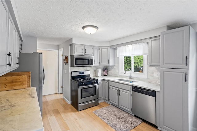 158 Round Pond Ln, Greece, NY 14626 - kitchen with appliances with stainless steel finishes, gray cabinetry, light wood-style flooring, light countertops, and tasteful backsplash