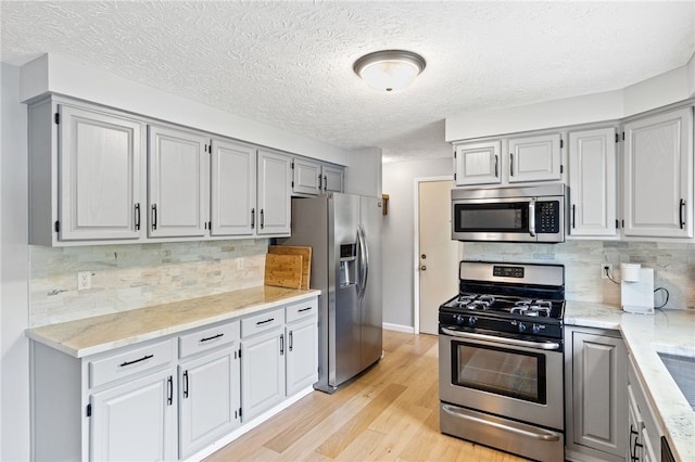 158 Round Pond Ln, Greece, NY 14626 - kitchen with stainless steel appliances, light wood-style flooring, gray cabinets, a textured ceiling, and backsplash