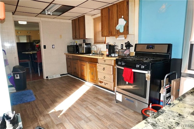 104 Argus St, Buffalo, NY 14207 - kitchen featuring gas range, light countertops, brown cabinets, wood finished floors, and a paneled ceiling