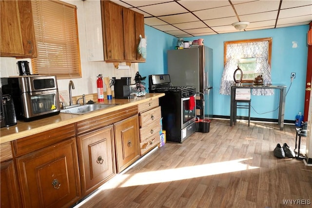 104 Argus St, Buffalo, NY 14207 - kitchen featuring stainless steel appliances, brown cabinetry, light wood-style flooring, a drop ceiling, and light countertops