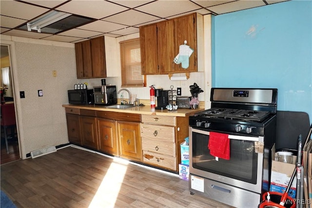 104 Argus St, Buffalo, NY 14207 - kitchen with stainless steel range with gas cooktop, black microwave, light countertops, brown cabinetry, and wood finished floors