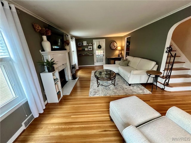 858 Starin Ave, Tonawanda, NY 14223 - living room featuring light wood-style flooring, a fireplace with flush hearth, arched walkways, stairs, and ornamental molding