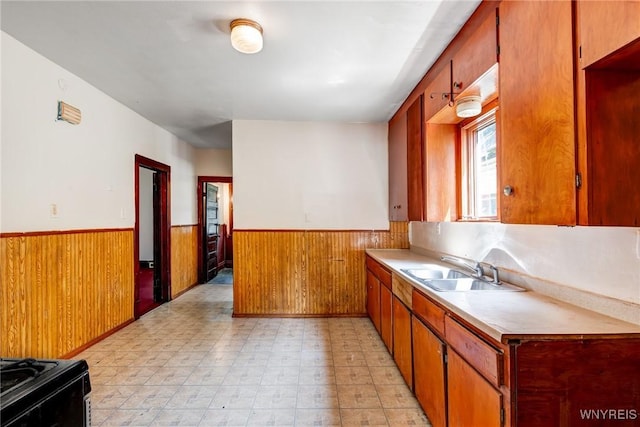 75 Schutrum St, Buffalo, NY 14212 - kitchen with a wainscoted wall, light countertops, black range oven, wood walls, and brown cabinetry